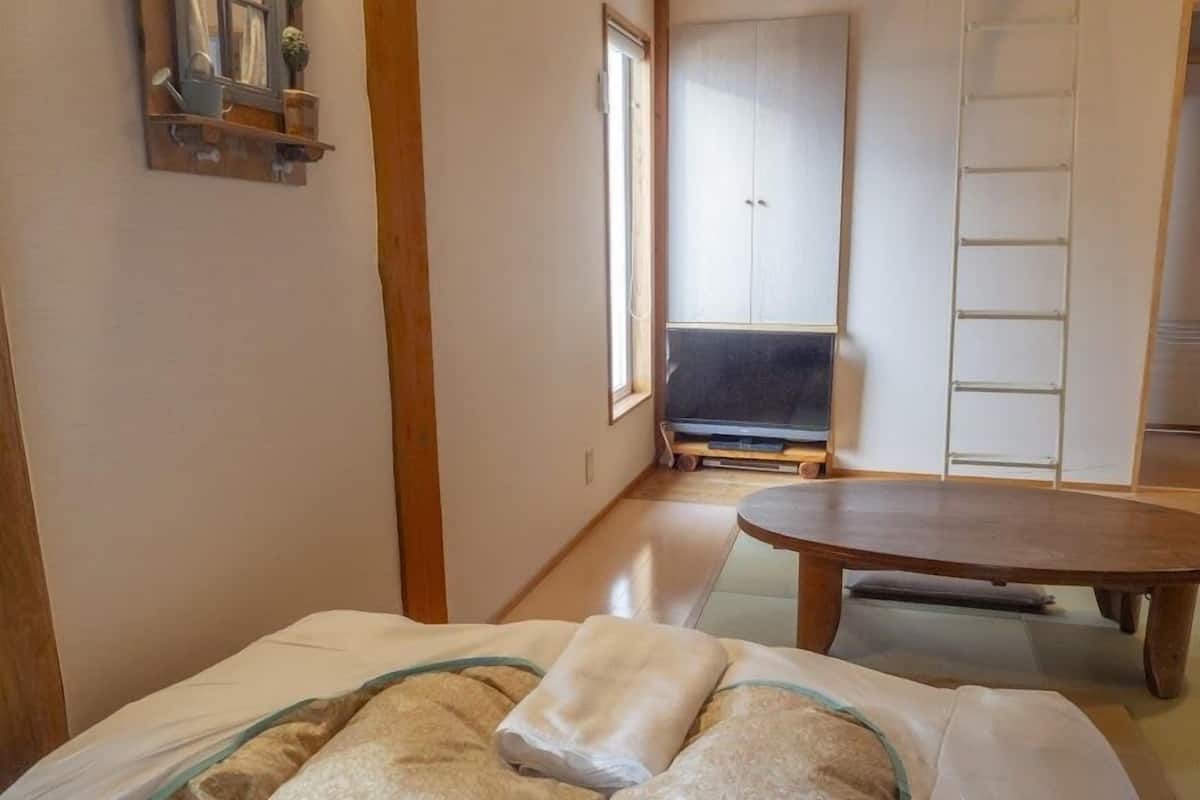 A room with a bed, a wooden table, a wardrobe, and a TV.