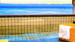 Un baño con pared de azulejos, una bañera y un lavabo amarillo.