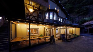 Un restaurante con terraza, una cubierta de madera y una escalera que lleva a un nivel superior.