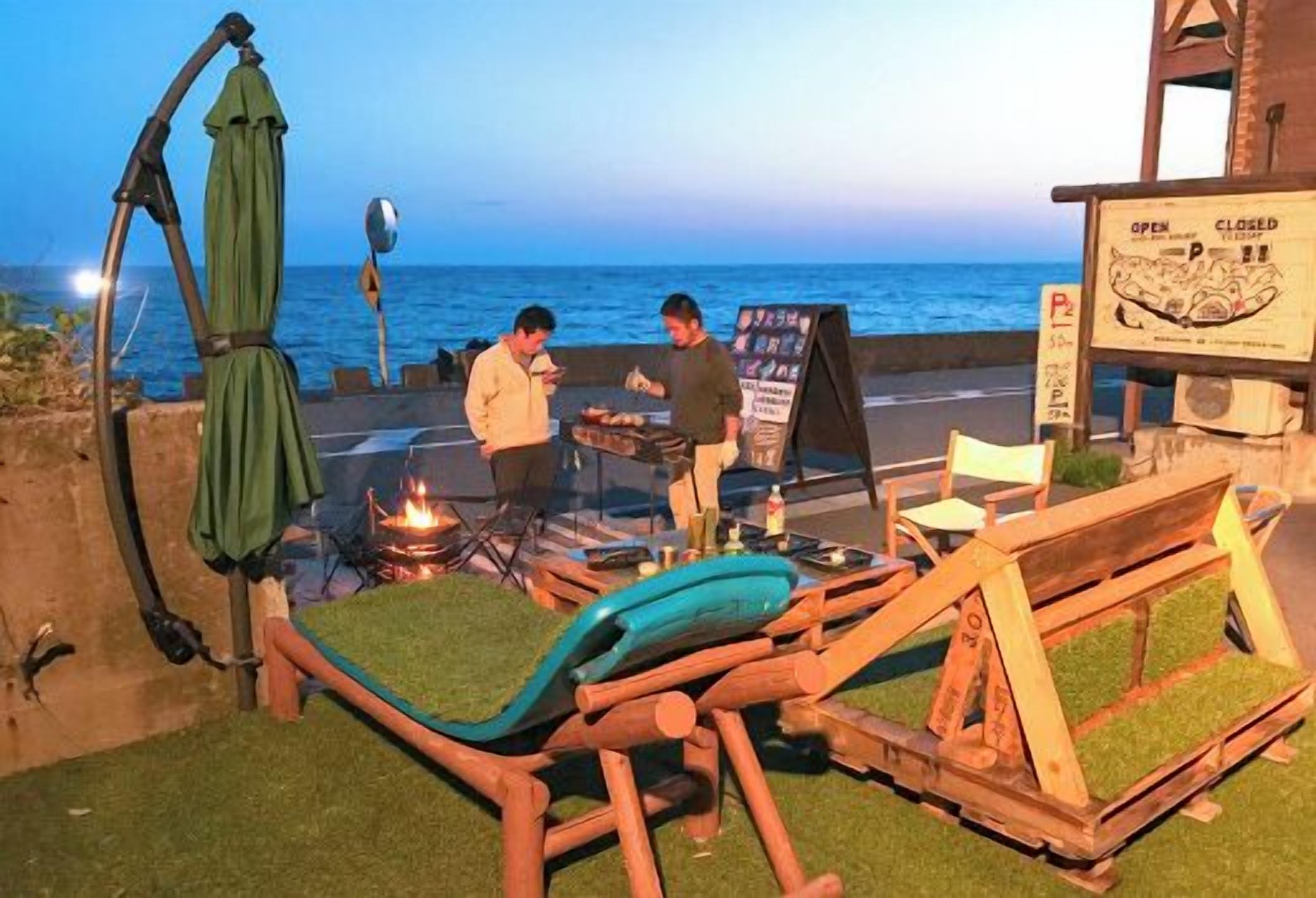 Een restaurant aan het strand met terras, een bord en uitzicht op de oceaan.
