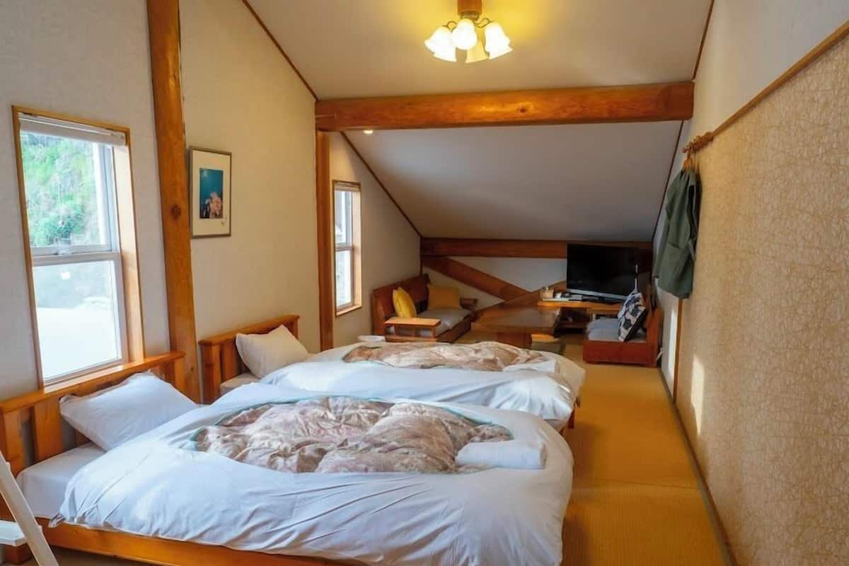 A bedroom with two beds, a TV, and a window.