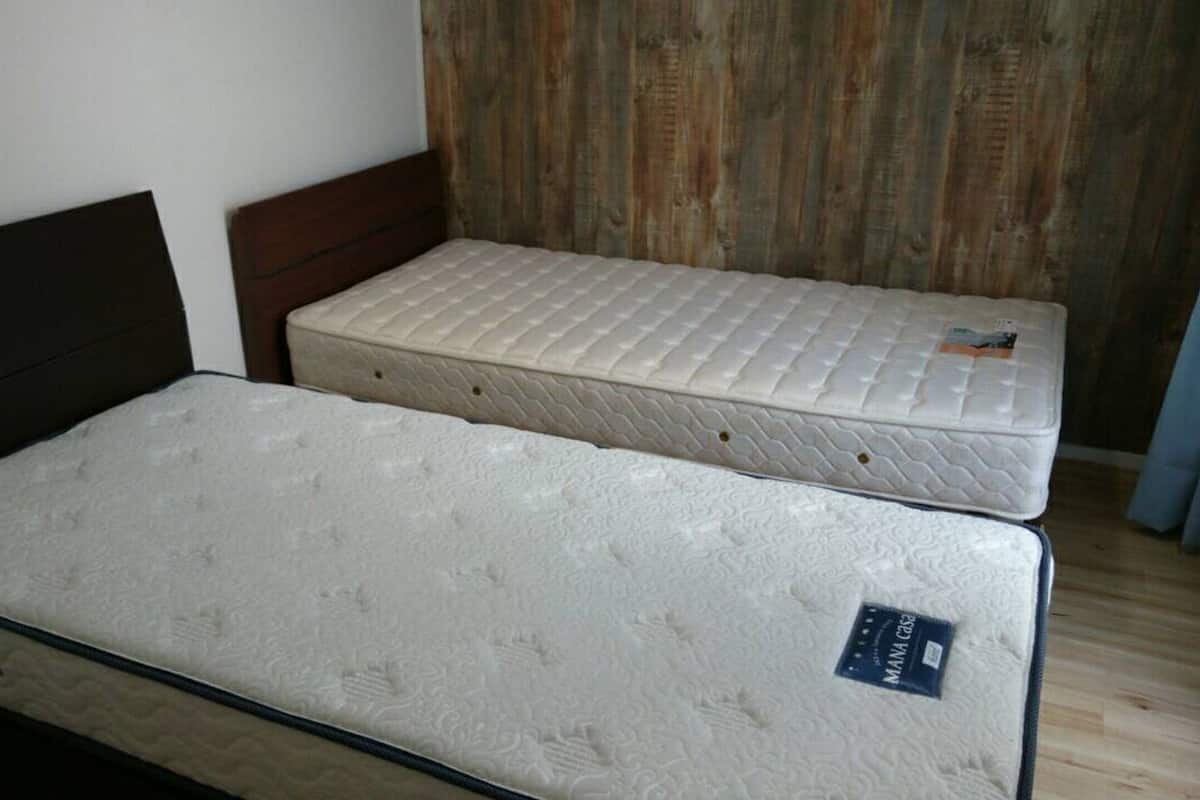 Una cama con cabecera de madera, colchón y un acolchado superior.