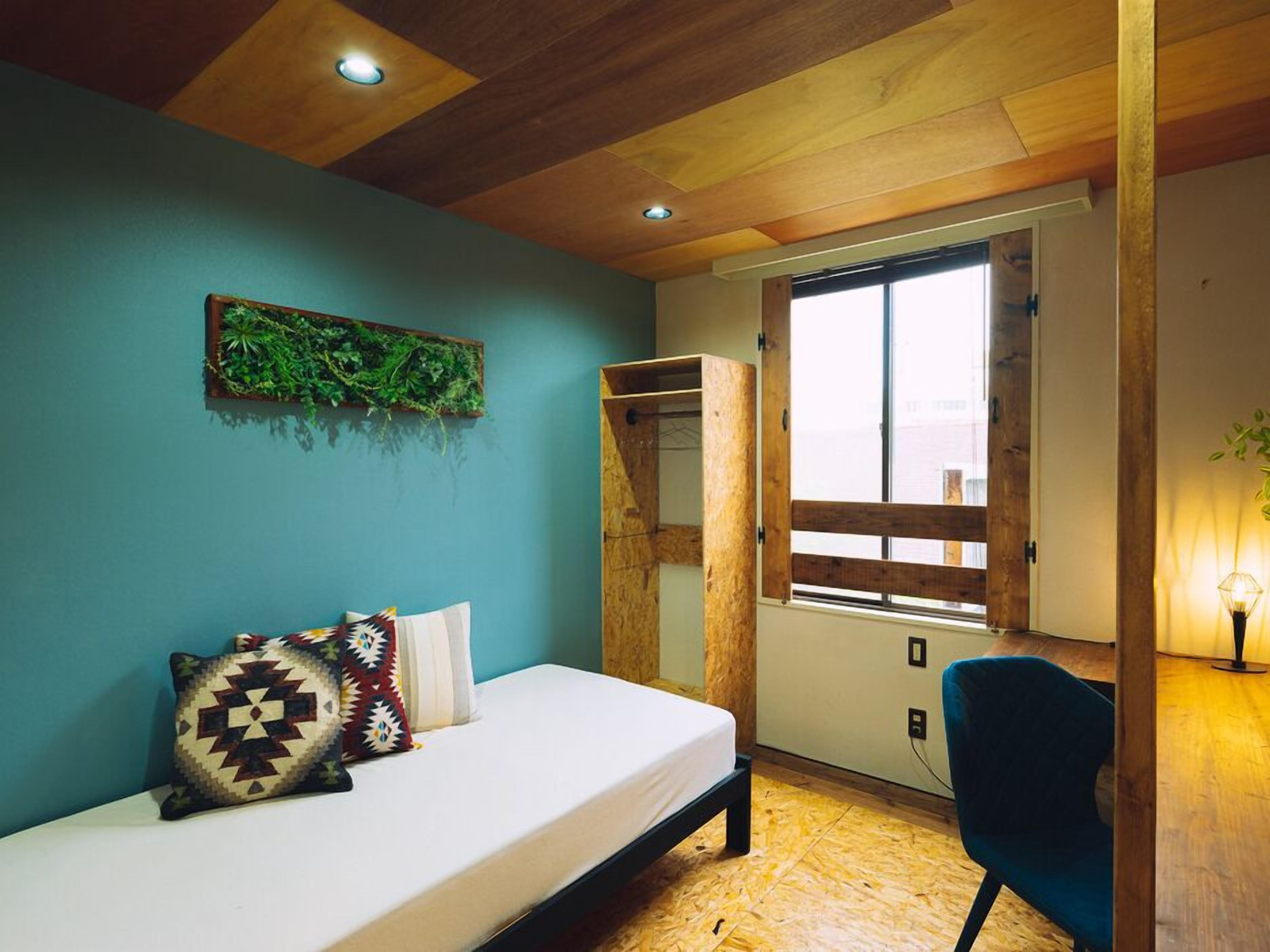Ein Schlafzimmer mit Bett, Fenster, Pflanze und Kleiderschrank.