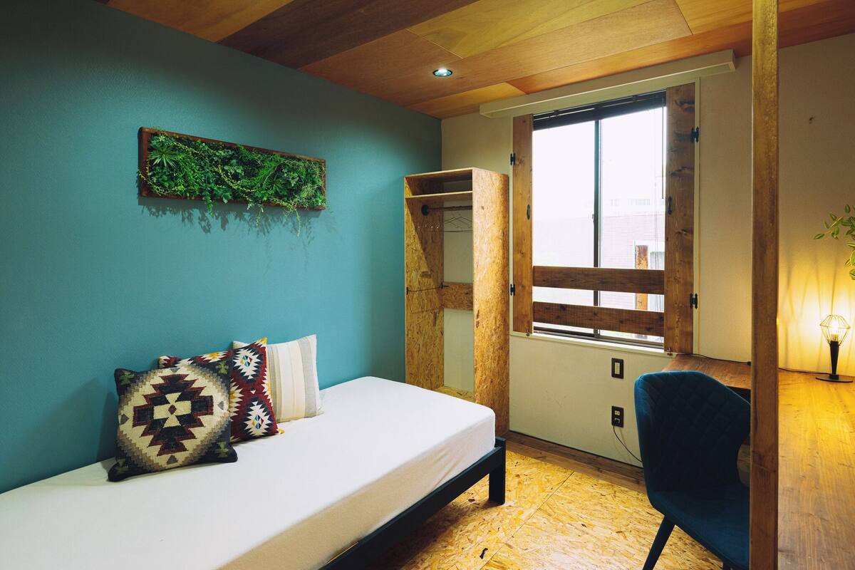 A bedroom with a bed, a window, and a wooden ceiling.