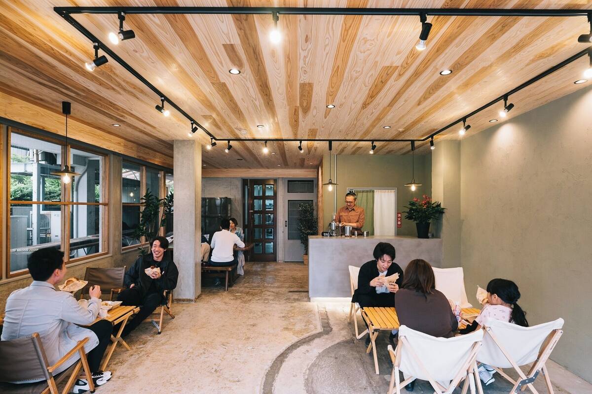 A modern interior with wooden ceiling, large windows, and a central seating area with tables and chairs.