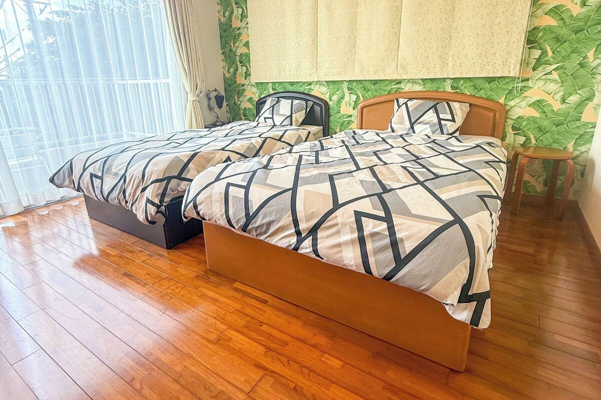 A double bed with a geometric patterned bedspread, a wooden headboard, and a small bedside table.