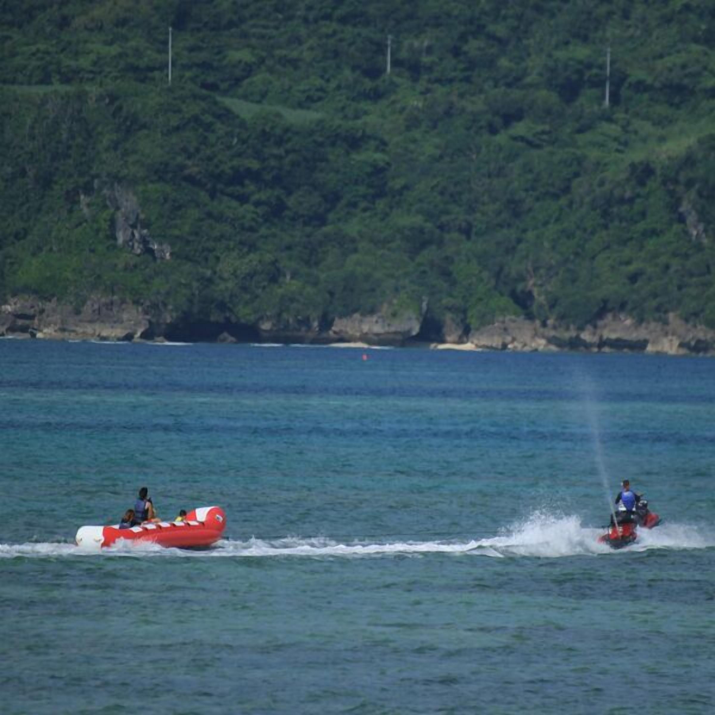 A red inflatable boat on calm water with a person in a blue shirt.