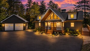 Ein modernes, zweigeschossiges Haus mit Garage, überdachter Veranda und gut beleuchteter Auffahrt.