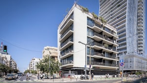 Un edificio de varios pisos con balcones, un paso de peatones y un semáforo.