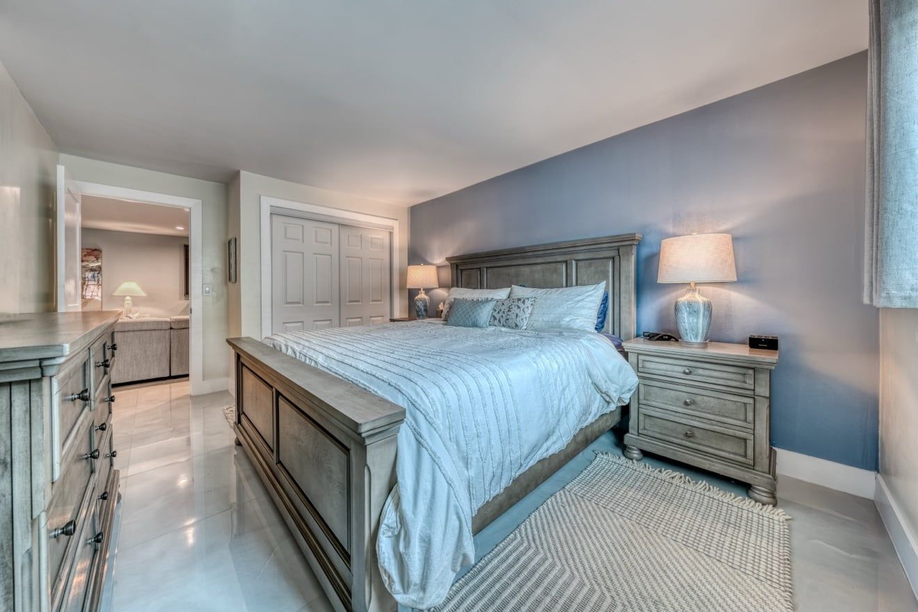 A bedroom with a large bed, bedside tables, and a wardrobe.