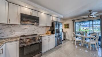A modern kitchen with white cabinetry, stainless steel appliances, and a dining area with a table and chairs.