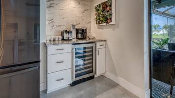 A kitchen with white cabinetry, a marble backsplash, and a coffee maker.