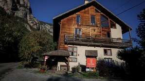 A wooden building with a balcony, a sign reading 'LES SAISONS,' and a mountain backdrop. - Hotel les 5 saisons (Freissinières)