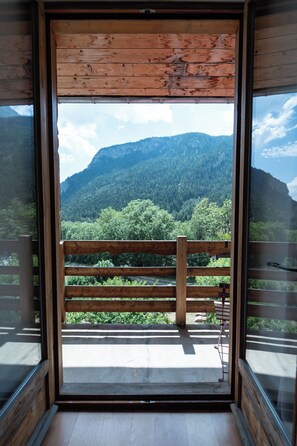 Un balcón de madera con vistas a una cadena montañosa boscosa.