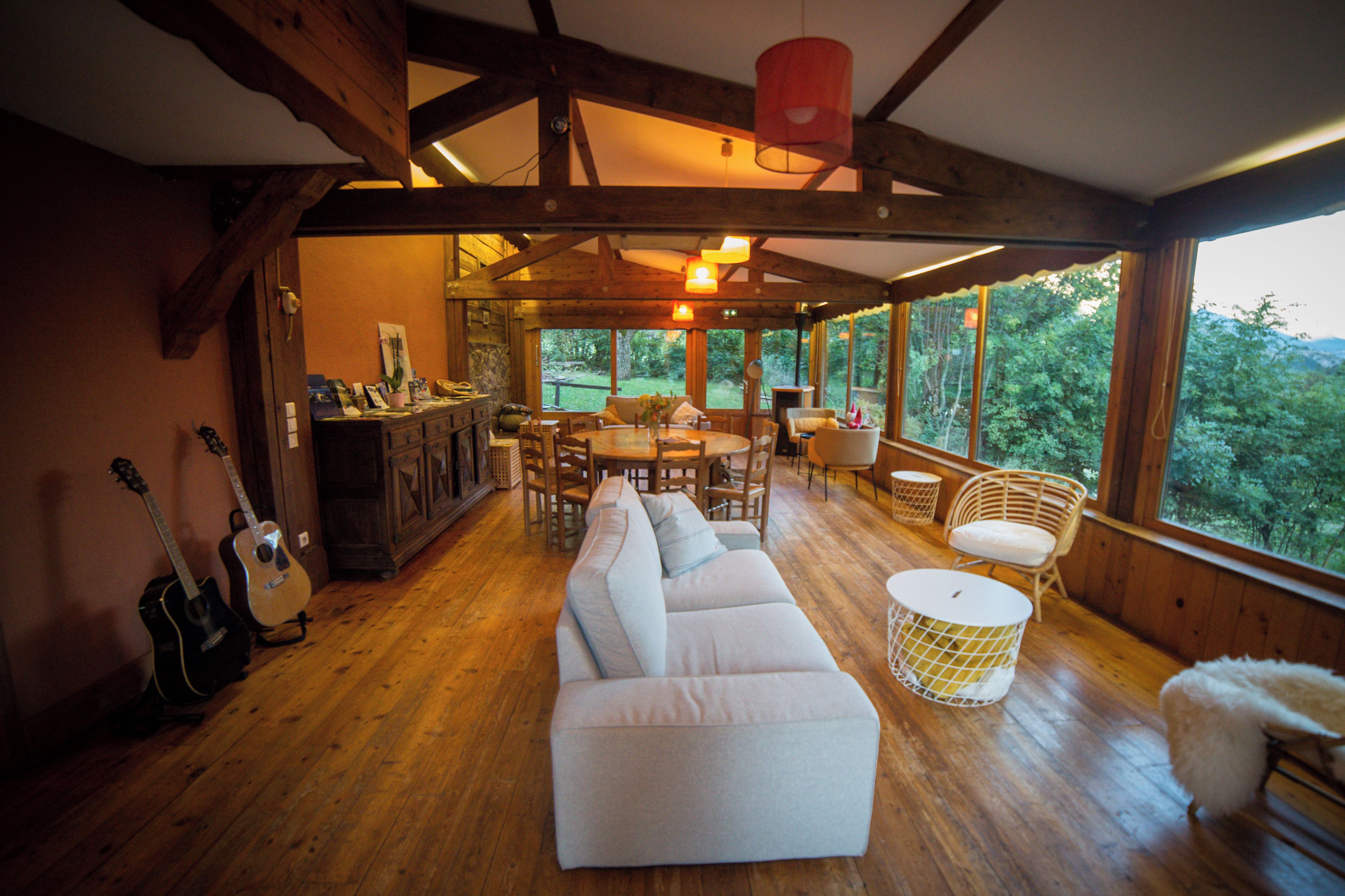 Un interior de madera con un sofá, una mesa de comedor, sillas y una guitarra.