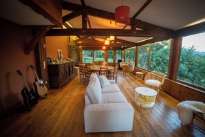 Un interior de madera con un sofá, una mesa de comedor, sillas y una guitarra.