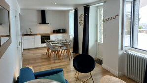Un appartamento moderno con zona pranzo, cucina e un'ampia finestra con tende.