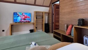 A room with a bed, a television, a speaker, and a wooden wall.
