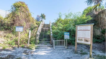 Una escalera que lleva a una zona de playa con carteles informativos sobre tortugas marinas.
