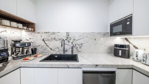 A modern kitchen with a built-in sink, a coffee machine, a microwave, and a toaster. - Veduta Tal-Marina (Airlie Beach)