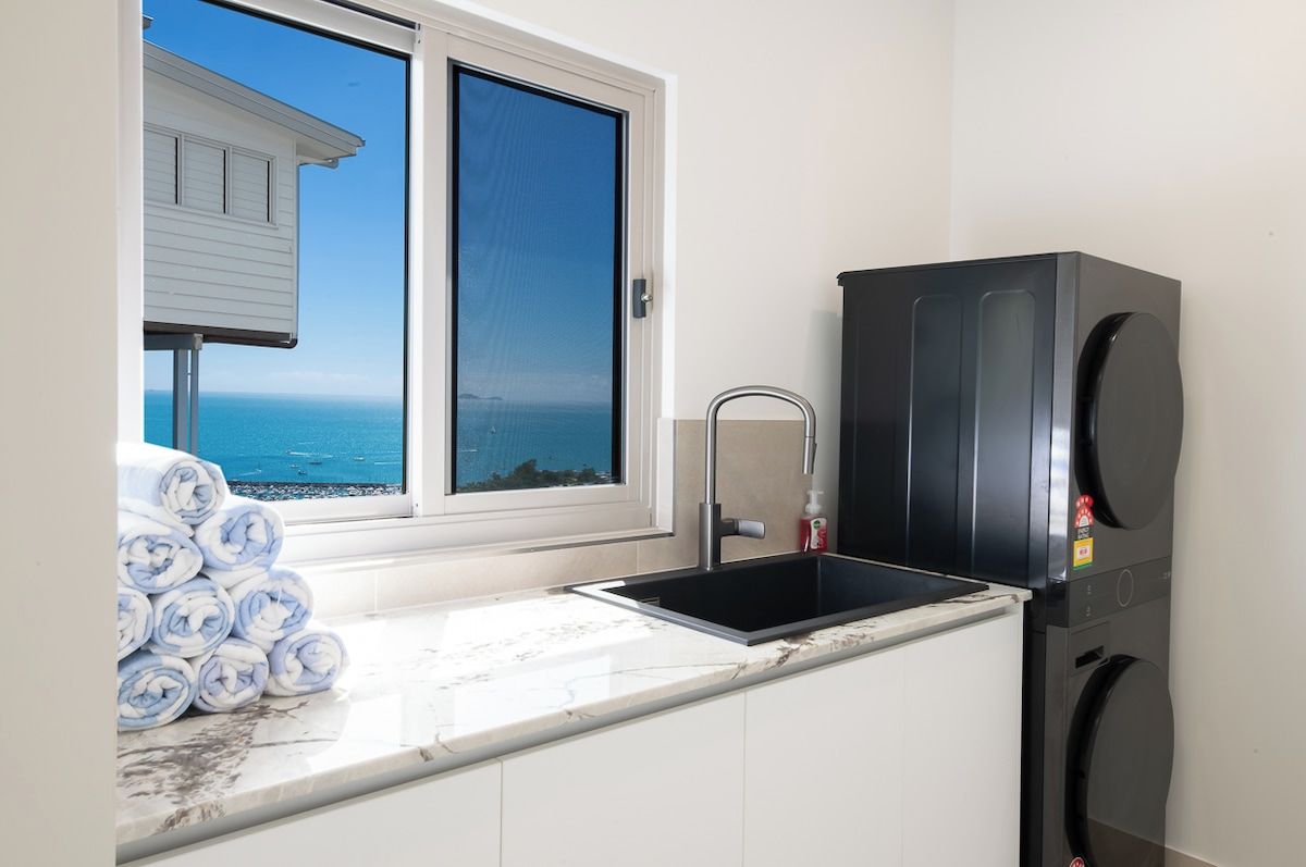 A kitchen with a sink, a black refrigerator, and a view of the ocean through a window.