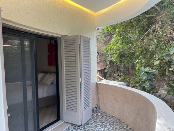Una habitación con una cama, una puerta corredera y vistas al verdor exterior.