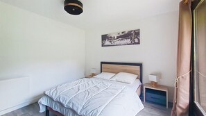 Ein Schlafzimmer mit einem Bett, zwei Nachttischen, einer Wandlampe und einem Gemälde.