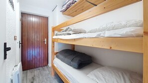 Ein Schlafzimmer mit Etagenbetten, einer Holztür und einem Thermostat an der Wand.