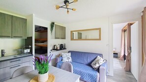 Ein gemütlicher, kleiner Wohnbereich mit Küchenzeile, Essbereich, Sofa und Spiegel.