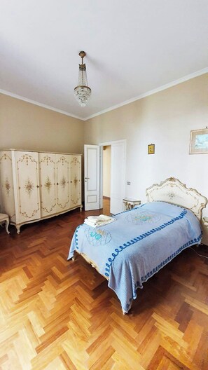 Ein Schlafzimmer mit einem Bett, einem Kleiderschrank, einer Chandelüster und einer Tür.