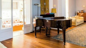 Ett rum med ett piano, en soffa, ett skåp och en dörr som leder till ett annat rum.