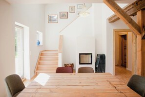 Ein Essbereich mit Holztisch, Stühlen, einer Treppe und einem an der Wand befestigten Fernseher.