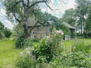 Ein rustikales Holzhaus, umgeben von üppigem Grün und blühenden Pflanzen.