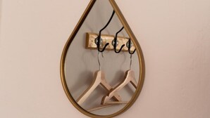 Un porte-manteau en bois à fixer au mur, doté d’un cadre transparent en forme de goutte.