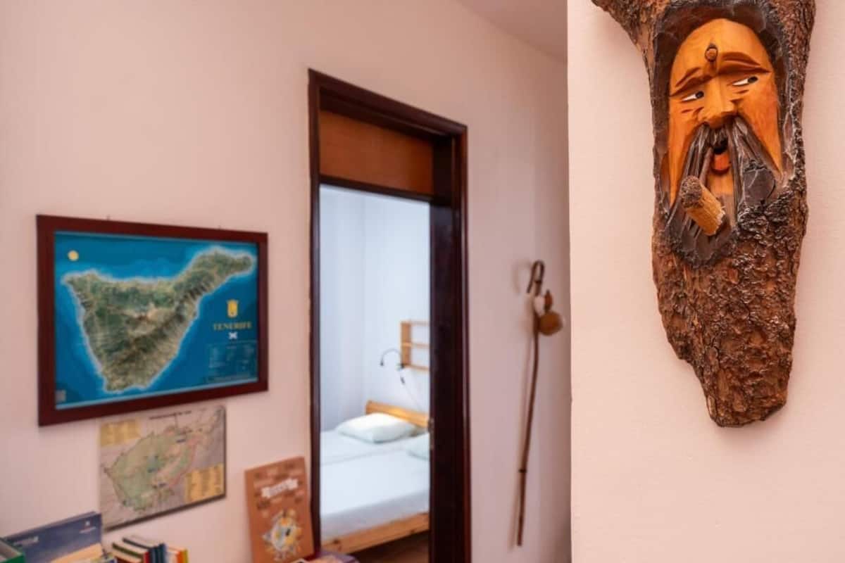 Une pièce avec un lit, une carte accrochée au mur et une sculpture en bois.
