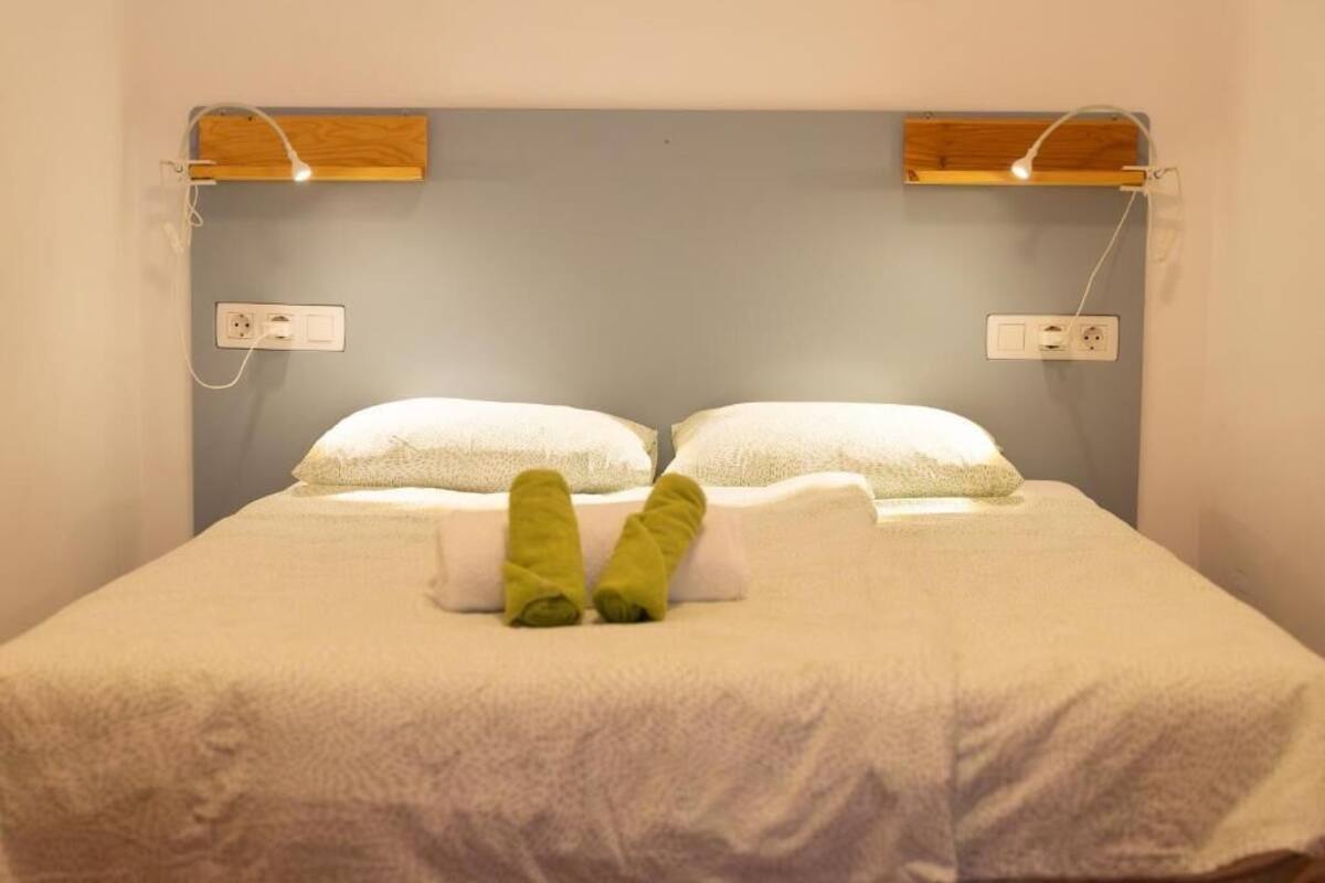 Un lit avec un matelas blanc, deux oreillers et une paire de serviettes vertes.