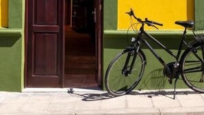 Une entrée d’immeuble avec une porte en bois, un vélo garé à l’extérieur et une affiche sur le mur.