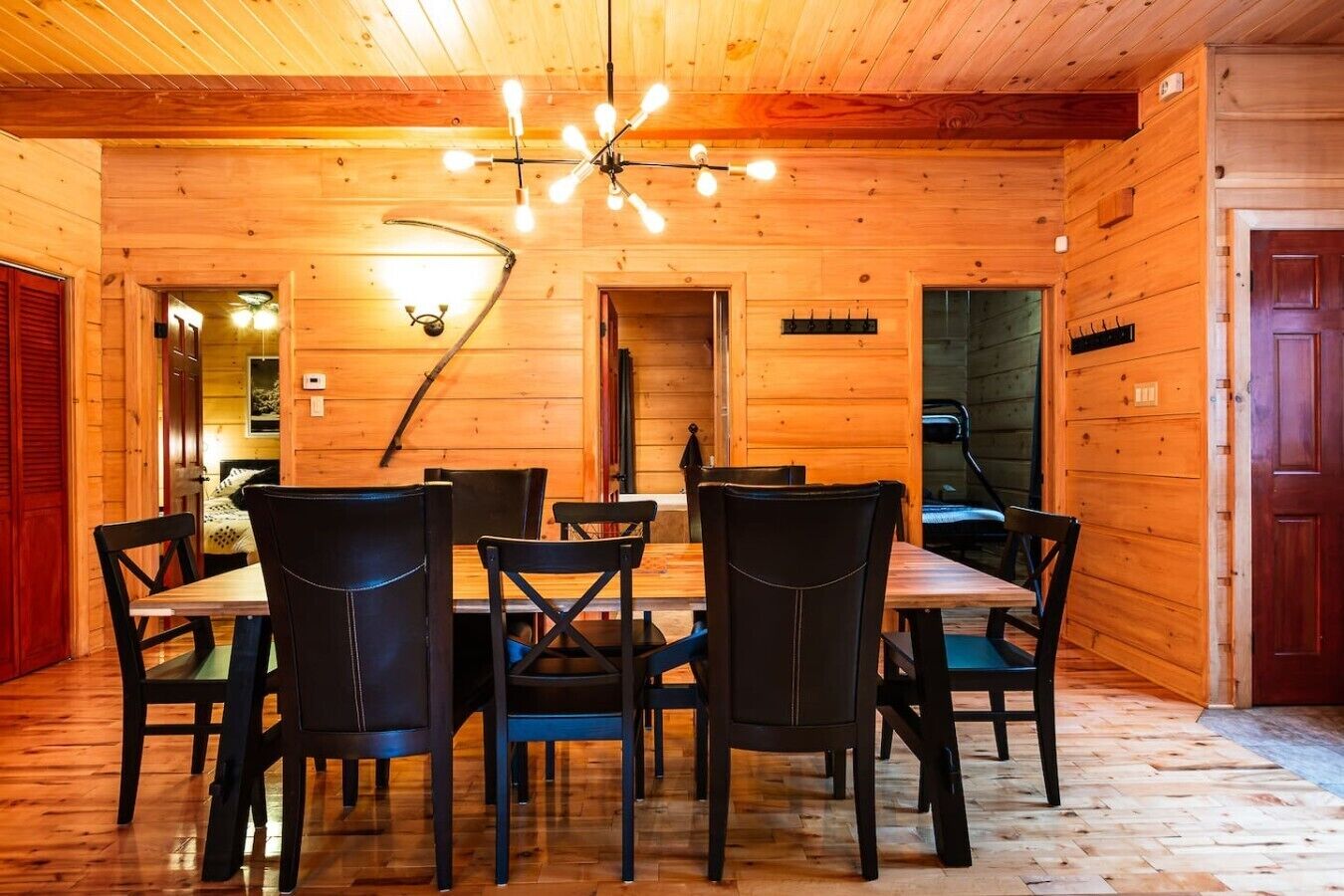 A wooden interior with a dining table and chairs, a ceiling light fixture, and a door.