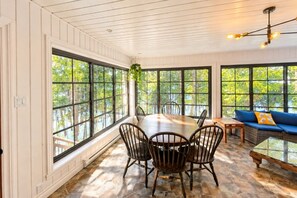 A dining area with a round table and chairs, large windows, and a blue sofa. - Chalet Brise du Nord (Matawinie Regional County Municipality)