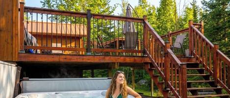A hot tub on a wooden deck with a staircase leading to a covered area.