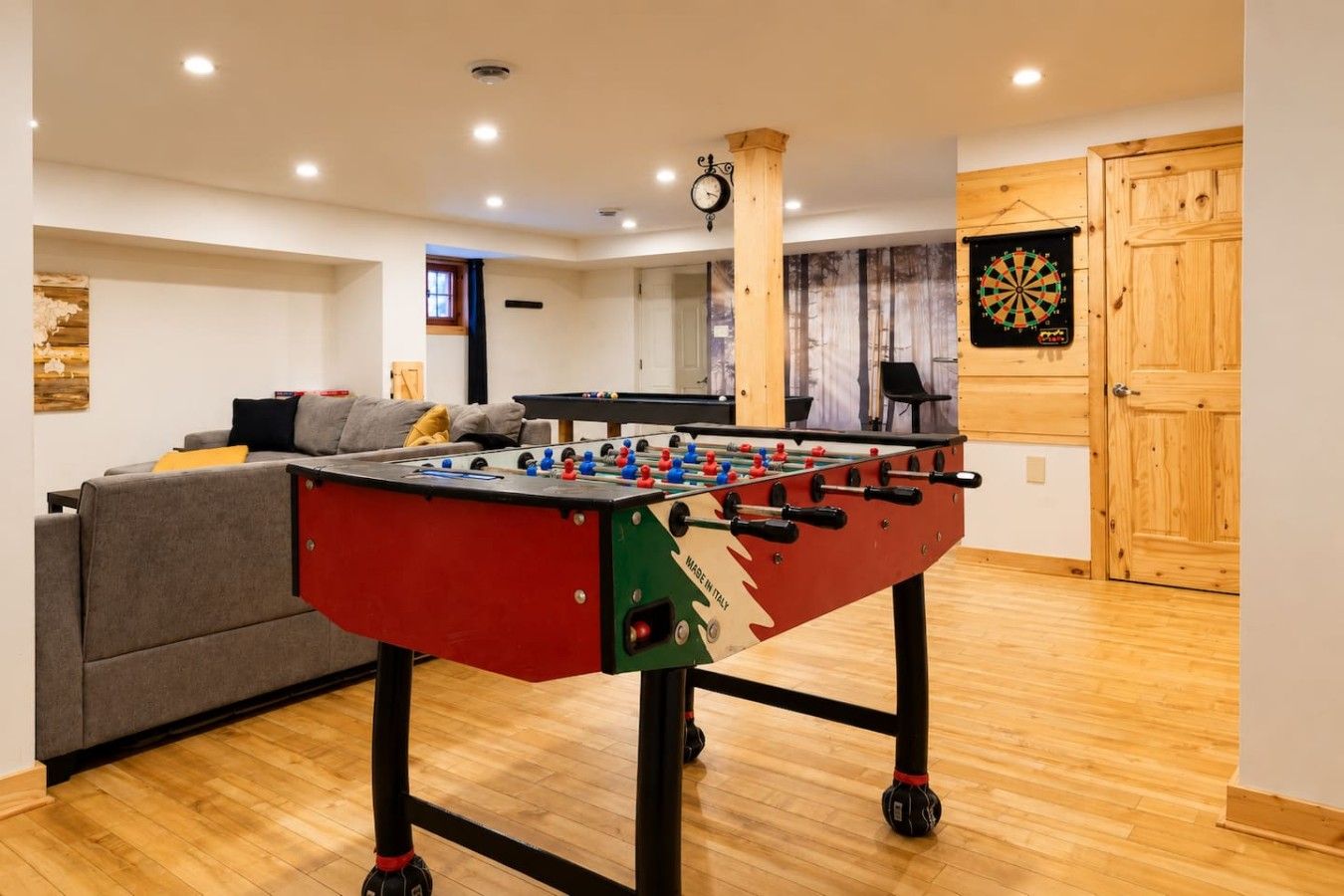 Una habitación con mesa de futbolín, dardos y un sofá.