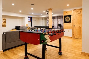 A room with a foosball table, a dartboard, and a sofa. - Chalet Brise du Nord (Matawinie Regional County Municipality)