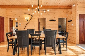 A wooden interior with a dining area featuring a table and chairs, a ceiling light fixture, and a wall-mounted light. - Chalet Brise du Nord (Matawinie Regional County Municipality)