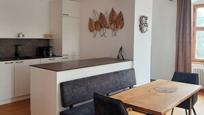 Eine moderne Küche mit weißen Schränken, einer Holz Arbeitsplatte und einer Sitzbank.