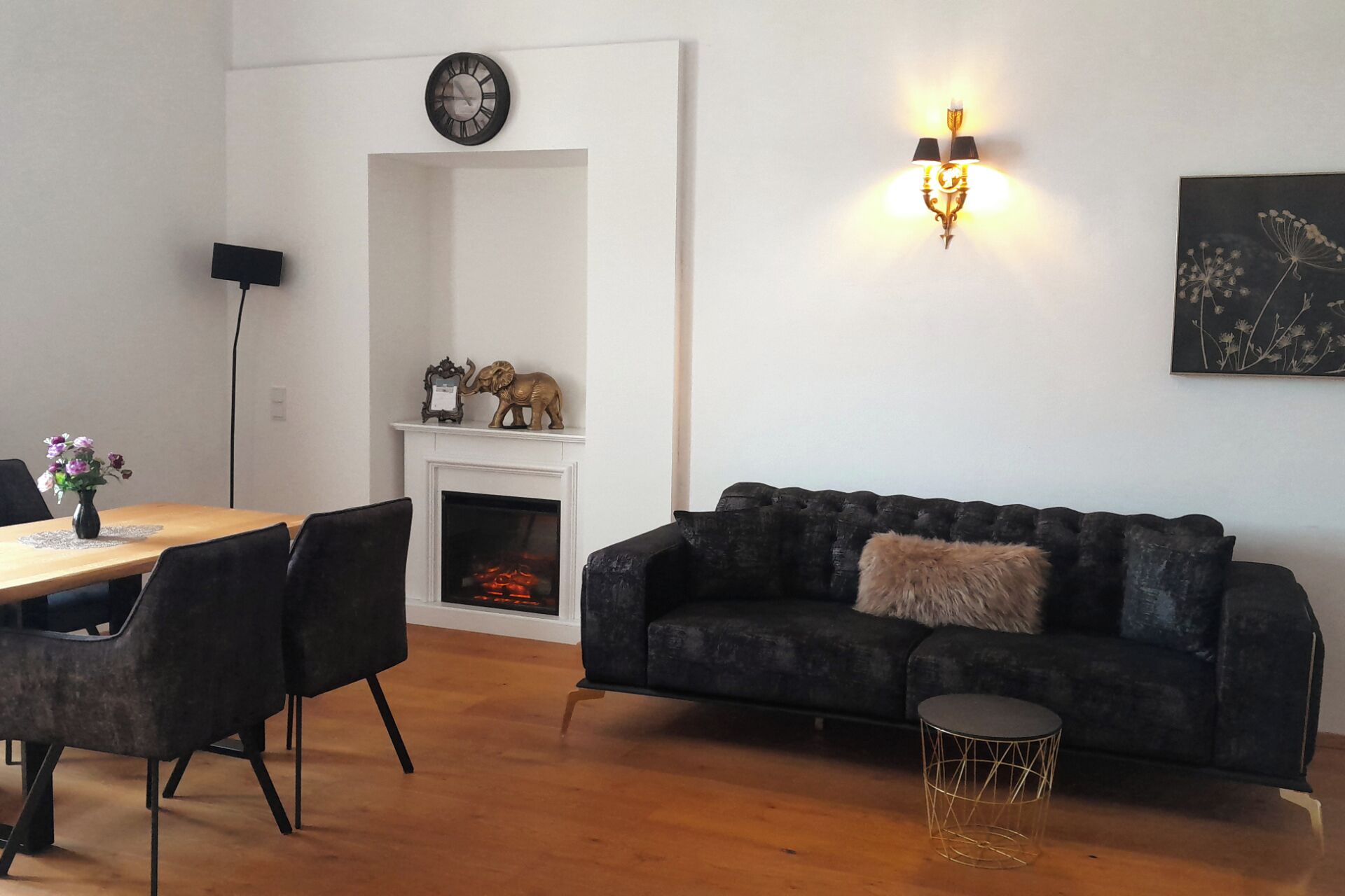 Una sala de estar con chimenea, sofá, mesa de centro y comedor con sillas.