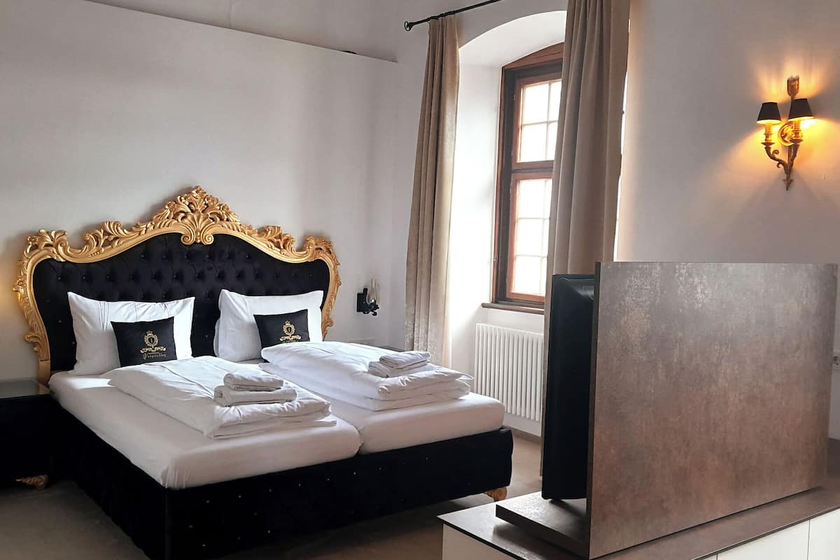 A hotel room with a large bed, a television, and a window with curtains.