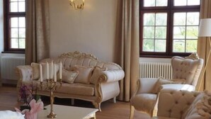 Ein Zimmer mit einem großen Fenster, einem Sofa, einem Tisch und einer Lampe.
