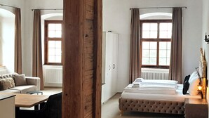 Ein Hotelzimmer mit Bett, Sofa, Schreibtisch und einem Fenster mit Vorhängen.