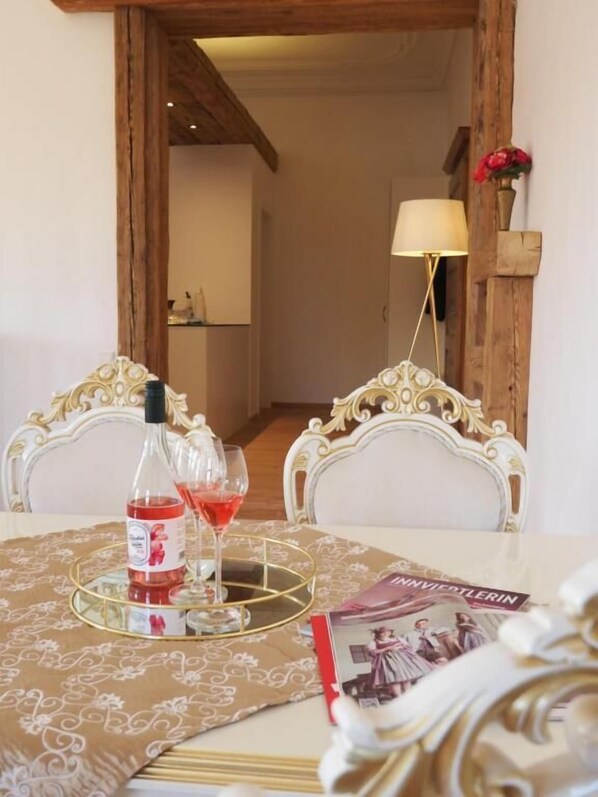 Una mesa de comedor con una botella de vino tinto, dos copas, una bandeja y una revista.