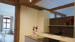 Eine moderne Küche mit Holzbalken, einer zentralen Kochinsel und Blick auf einen Essbereich.